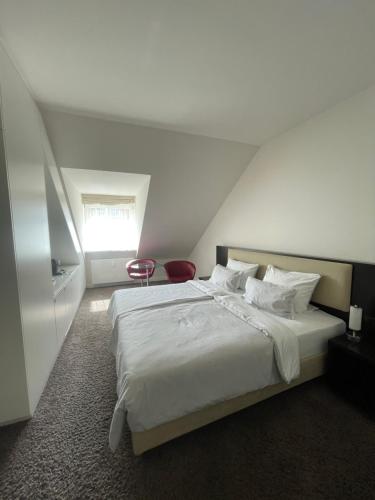 a bedroom with a white bed and a red chair at Hotel Kieler Yacht-Club in Kiel