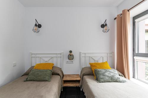 2 camas en una habitación con ventana en Apartamentos Rurales San Pedro en Valencia de Alcántara