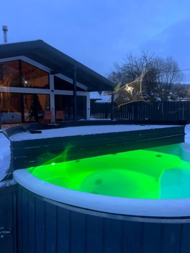 a hot tub with green illumination in front of a house at Boiko house in Slavske