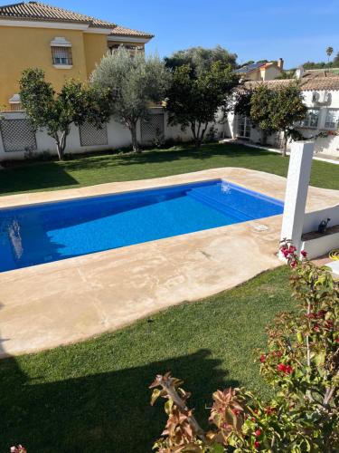 a swimming pool in a yard next to a house at Chalet Ciudad Ducal con piscina y jardin in El Puerto de Santa María