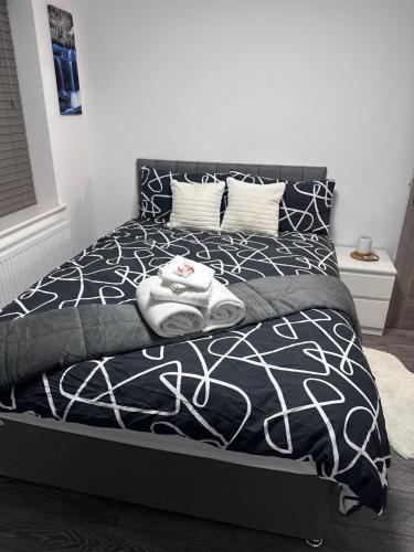 a bed with a black and white comforter and pillows at Stunning 2-flat in Leicester! in Leicester