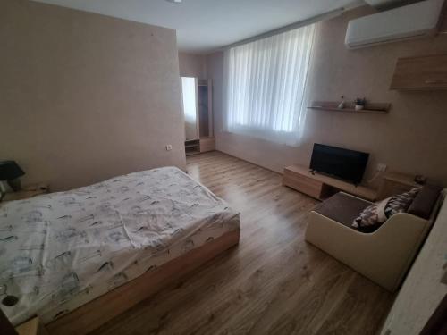 een slaapkamer met een bed, een bank en een televisie bij Къща за гости Люляк 