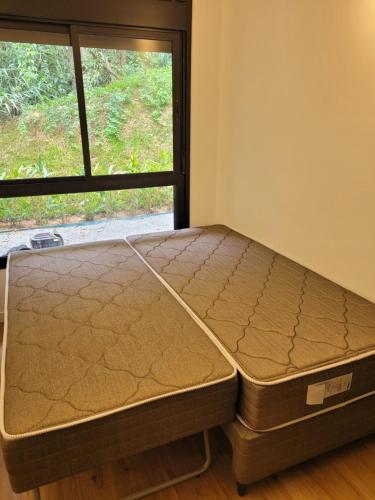 a bed sitting in a room next to a window at CHALÉ NAMATA 201 in São Roque