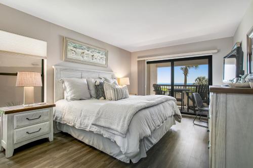 a bedroom with a bed and a balcony at Amelia Surf and Racquet in Fernandina Beach