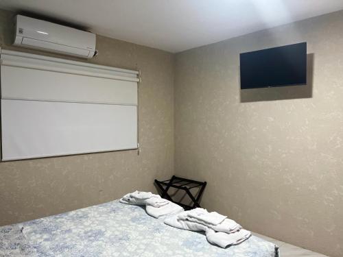 sypialnia z telewizorem i łóżkiem z ręcznikami w obiekcie GALASUITES w mieście Puerto Baquerizo Moreno