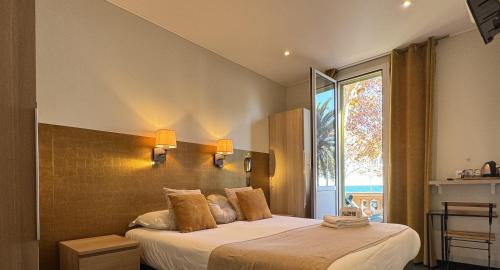 a bedroom with two beds and a large window at Hotel Pavillon Imperial in Menton