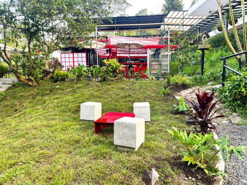 a red table and two white benches in a garden at Tierra Maravilla in Salento