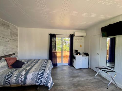 Maison LeBreux - Motel في Petite-Vallée: غرفة نوم بسرير وتلفزيون على سقف