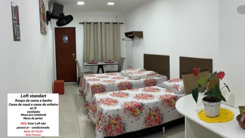 um quarto de hotel com duas camas e uma mesa em Loft Casa Feliz em Rio das Ostras