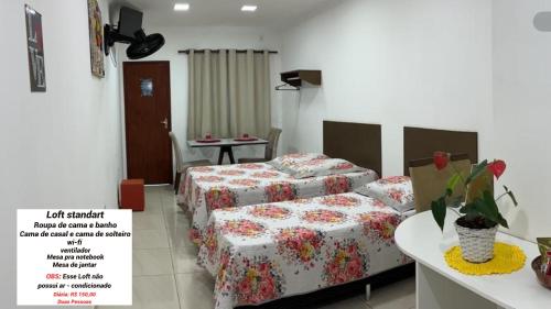 a hotel room with two beds and a table at Loft Casa Feliz in Rio das Ostras