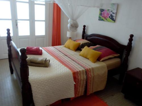 1 dormitorio con 1 cama con almohadas amarillas y rojas en KAZ A FAUP, en Grand-Bourg