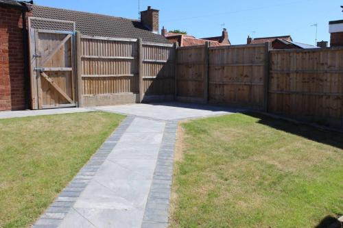 a backyard with a wooden fence and a driveway at Remarkable 2-Bed House in Walesby Nottinghamshire in Elkesley