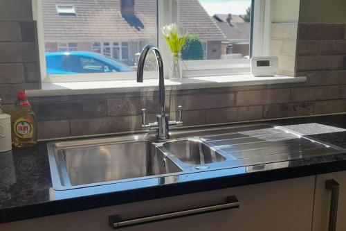 een roestvrijstalen wastafel in een keuken met een raam bij Remarkable 2-Bed House in Walesby Nottinghamshire in Elkesley