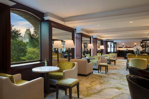a hotel lobby with chairs and tables and a large window at The Ritz-Carlton New York, Central Park in New York