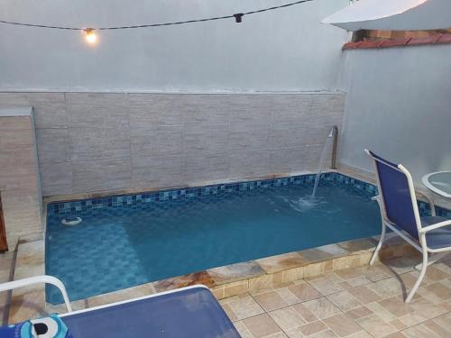 a small swimming pool with two chairs and a table at Doce Refugio Itanhaém in Itanhaém