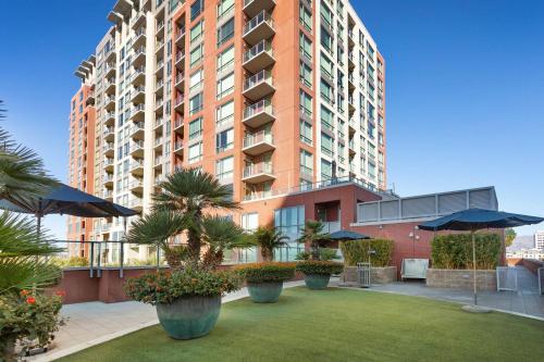 a large apartment building with palm trees and umbrellas at Global Luxury Suites San Jose Downtown in San Jose