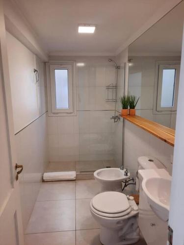 a white bathroom with a toilet and a sink at La Fragua Suites Líbano in El Bolsón