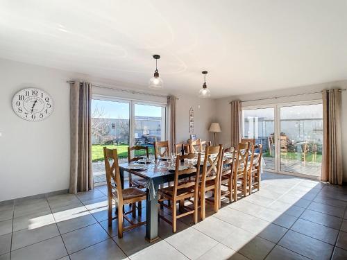 une salle à manger avec une table, des chaises et une horloge dans l'établissement Grande maison de vacances, à Agon-Coutainville
