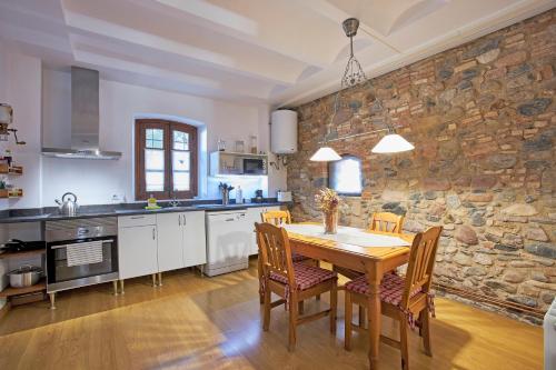 cocina con mesa de madera y pared de piedra en Mas Can Calet Aparthotel, en Les Franqueses del Vallès