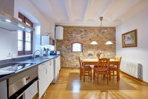 a kitchen with a table and chairs and a stone wall at Mas Can Calet Aparthotel in Les Franqueses del Vallès