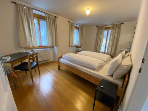 a bedroom with a bed and a desk and windows at Pension Bellevue Gondo in Ruden