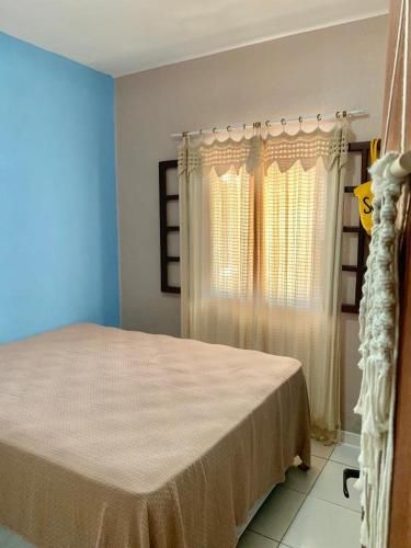 a bedroom with a bed and a window with curtains at Quarto com Área gourmet e piscina privativo in São João da Barra