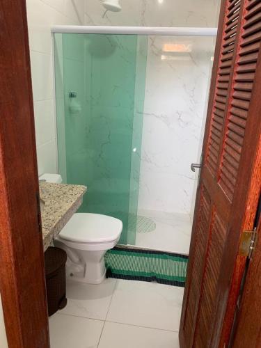 a bathroom with a toilet and a glass shower at Quarto com Área gourmet e piscina privativo in São João da Barra