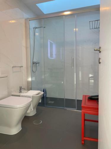 a bathroom with a shower and a toilet and a red table at Casa do Cabo in Mós