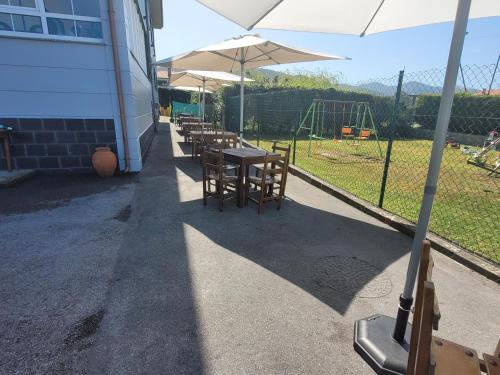 a group of tables and chairs with an umbrella at Hotel Restaurante el Fornon in Novellana