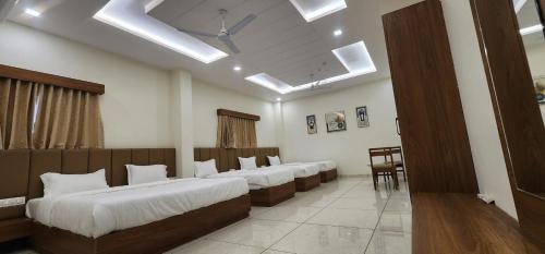 Habitación con 4 camas seguidas en una habitación en Hotel Grand Ekta en Godhra