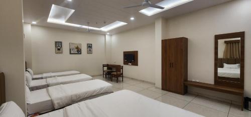 Habitación de hotel con 2 camas y espejo en Hotel Grand Ekta en Godhra