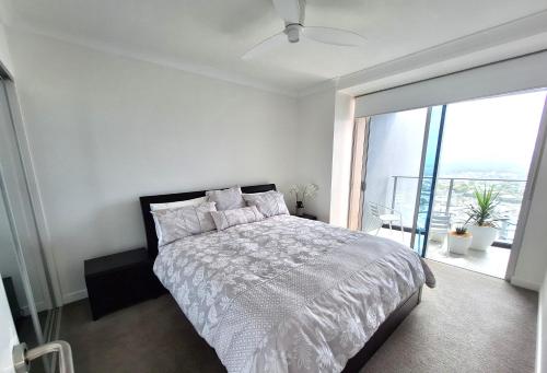 Dormitorio blanco con cama y ventana grande en Southport central Lux 1 Bedroom en Gold Coast