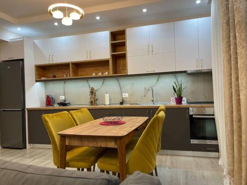 a kitchen with a wooden table and yellow chairs at Melody Apartment in Korçë in Korçë