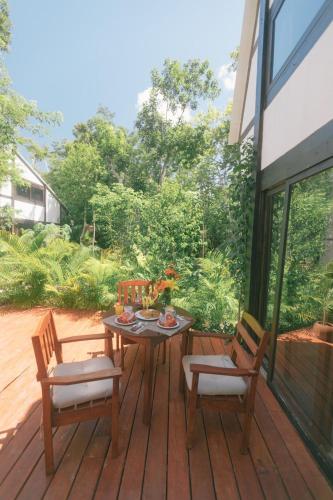 a wooden table and two chairs on a deck at Nahouse Jungle Lodges in Tulum