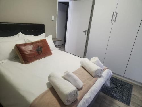 uma cama branca com toalhas e uma bolsa em The Galton Villa em Windhoek