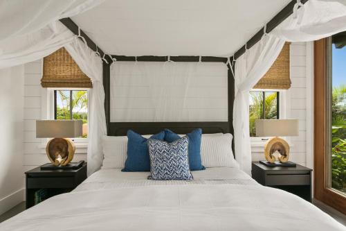 - une chambre avec un grand lit blanc et des oreillers bleus dans l'établissement Kukui'ula Luxury Vacation Home 62- Alekona Kauai, à Koloa