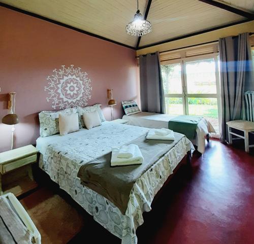 um quarto com 2 camas e uma grande janela em Pousada Paralelo 14 em Alto Paraíso de Goiás