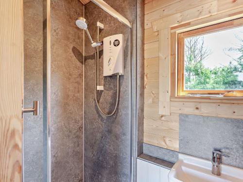 a shower in a wooden bathroom with a sink at 1 Bed in Weston-Super-Mare 91933 in Yatton