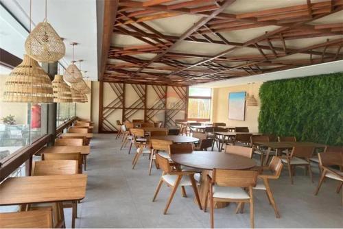 un ristorante con tavoli e sedie e una parete verde di Makia Beach Experience - D 202 a Porto De Galinhas
