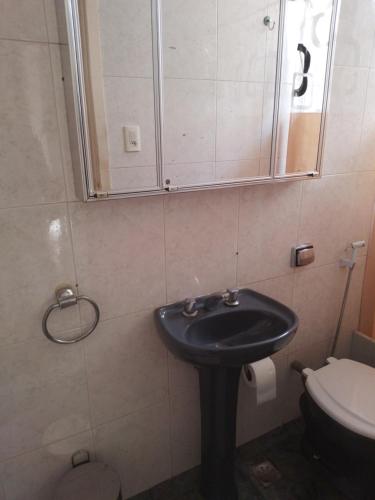 La salle de bains est pourvue d'un lavabo, d'un miroir et de toilettes. dans l'établissement Apartamento aconchegante, à Rio de Janeiro