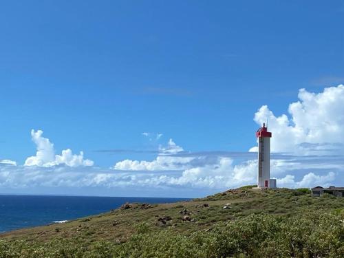 a lighthouse sitting on top of a hill next to the ocean at KARIFUNA in Le Souffleur