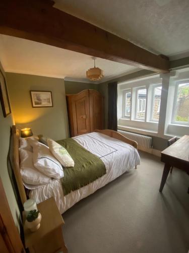 a bedroom with a bed in a room with windows at The Weavers Cottage in Oxenhope