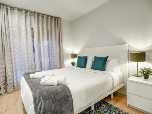 een witte slaapkamer met een groot bed met blauwe kussens bij Luxe Apartment by Hello Homes Sitges in Sitges