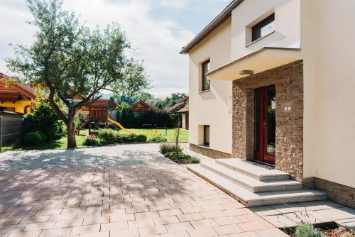 a house with a brick driveway next to a building at KAPINA sk - Dom Jasna in Liptovský Mikuláš