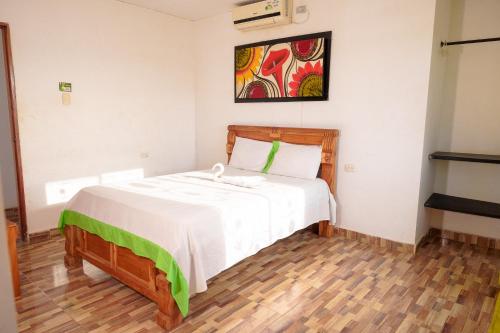 - une chambre dotée d'un lit avec des draps blancs et un tableau dans l'établissement Hotel Puertas del Norte, à Lorica