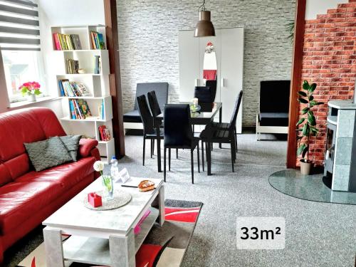 sala de estar con sofá rojo y mesa en Ferienwohnung "Blick Mylau" - Nähe Freizeitpark Plohn & Göltzschtalbrücke, en Reichenbach im Vogtland