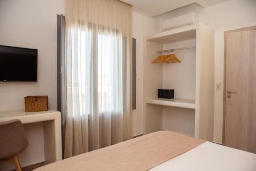 a bedroom with a bed and a window and a television at Anais Of Naxos in Agia Anna Naxos