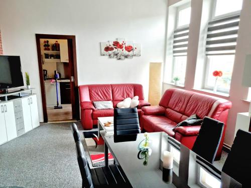 ein Wohnzimmer mit einem roten Sofa und einem Tisch in der Unterkunft Ferienwohnung "Blick Mylau" - Nähe Freizeitpark Plohn & Göltzschtalbrücke in Reichenbach im Vogtland