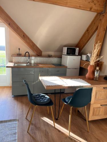 a kitchen with a table and two blue chairs at Gîte de l'Orme L'Horizon in Nanteau-sur-Essonnes