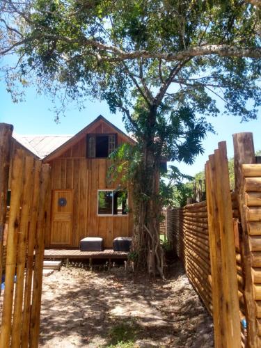 a wooden fence with a bench in front of a tree at Casa do Campo in Ilha do Mel